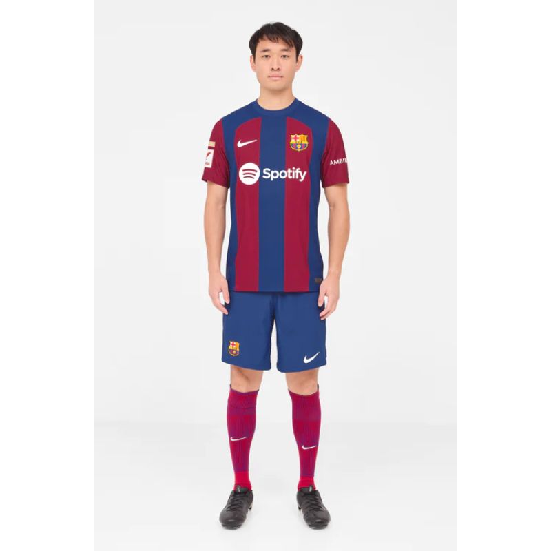 Man wearing Lamine Yamal Barcelona jersey with blue and red stripes, paired with matching shorts and socks